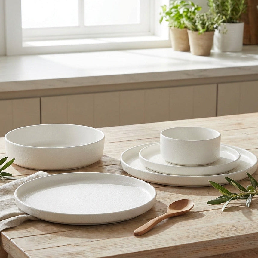 White ceramic dishes on a wooden table with a kitchen setting in the background