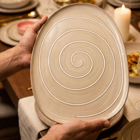 Person holding a ceramic plate with spiral design in a dining setting