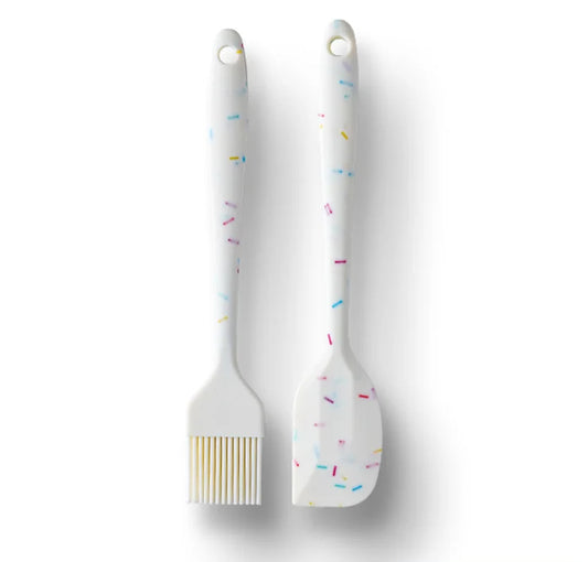 Two white silicone brushes with colorful sprinkles on a light gray background