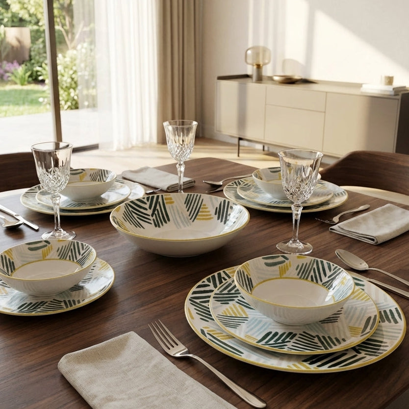 Dining table set with patterned plates, bowls, and cutlery in a bright room.