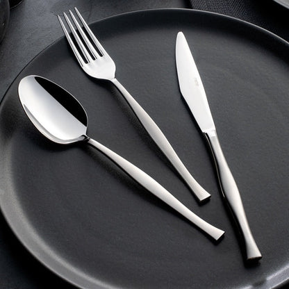 A set of silver cutlery including a soup ladle, service spoon, service fork, and a knife and fork set displayed on a dark plate.