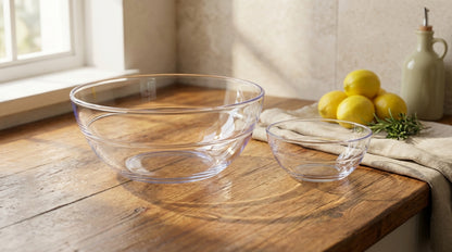 Clear glass bowls on a wooden table with lemons and a bottle in the background.