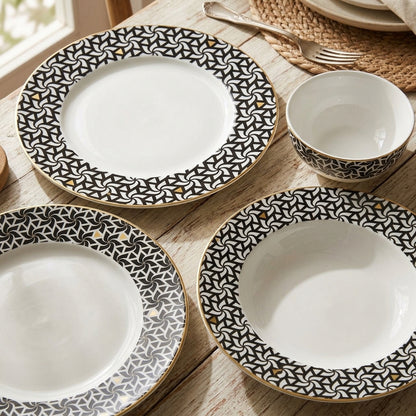 Set of ceramic plates with black geometric patterns on a wooden table.