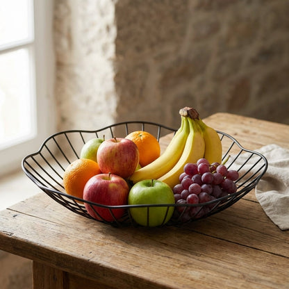 Fruit bowl with apples, oranges, bananas, and grapes on a wooden table.