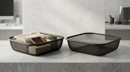 Two black mesh rectangular storage baskets with lids on a light gray stone countertop, with a folded beige towel, wooden block, and small succulent in one basket.