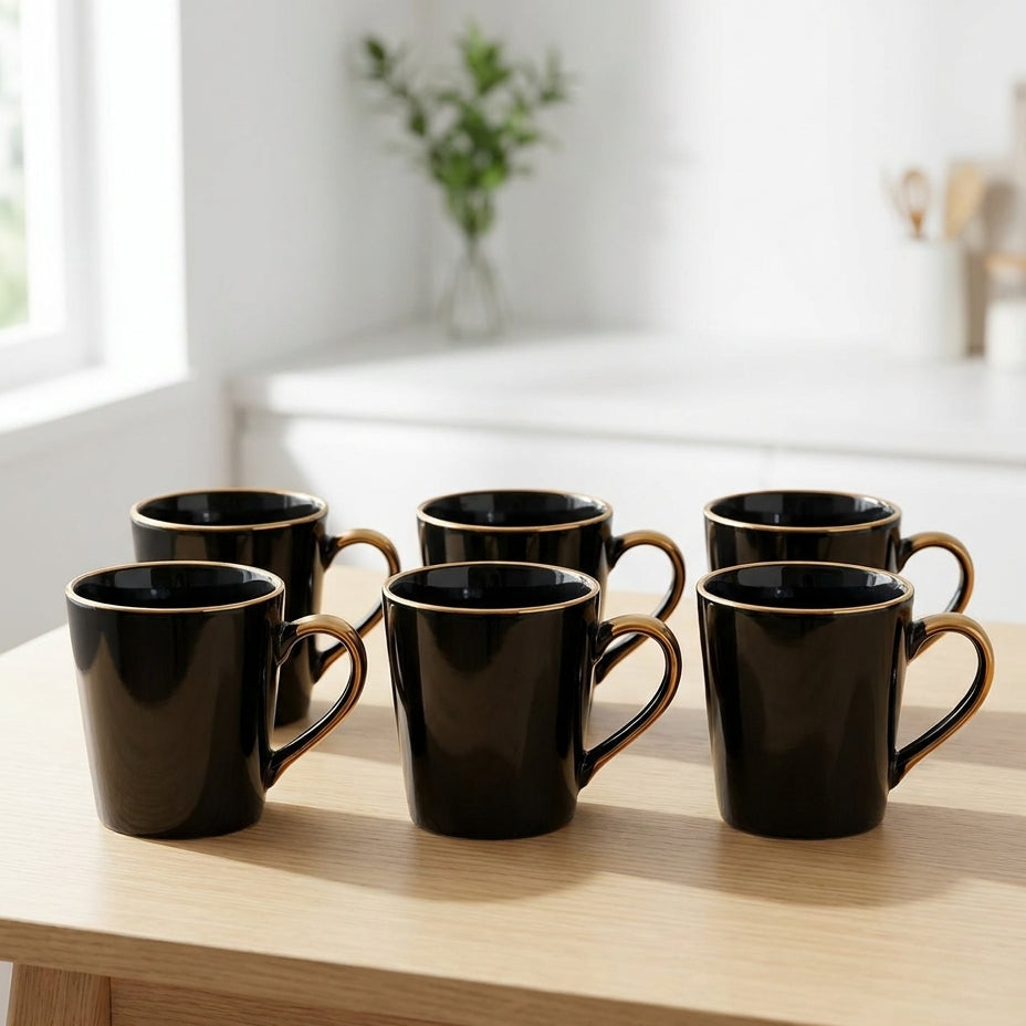 Set of black mugs on a wooden table in a bright kitchen.