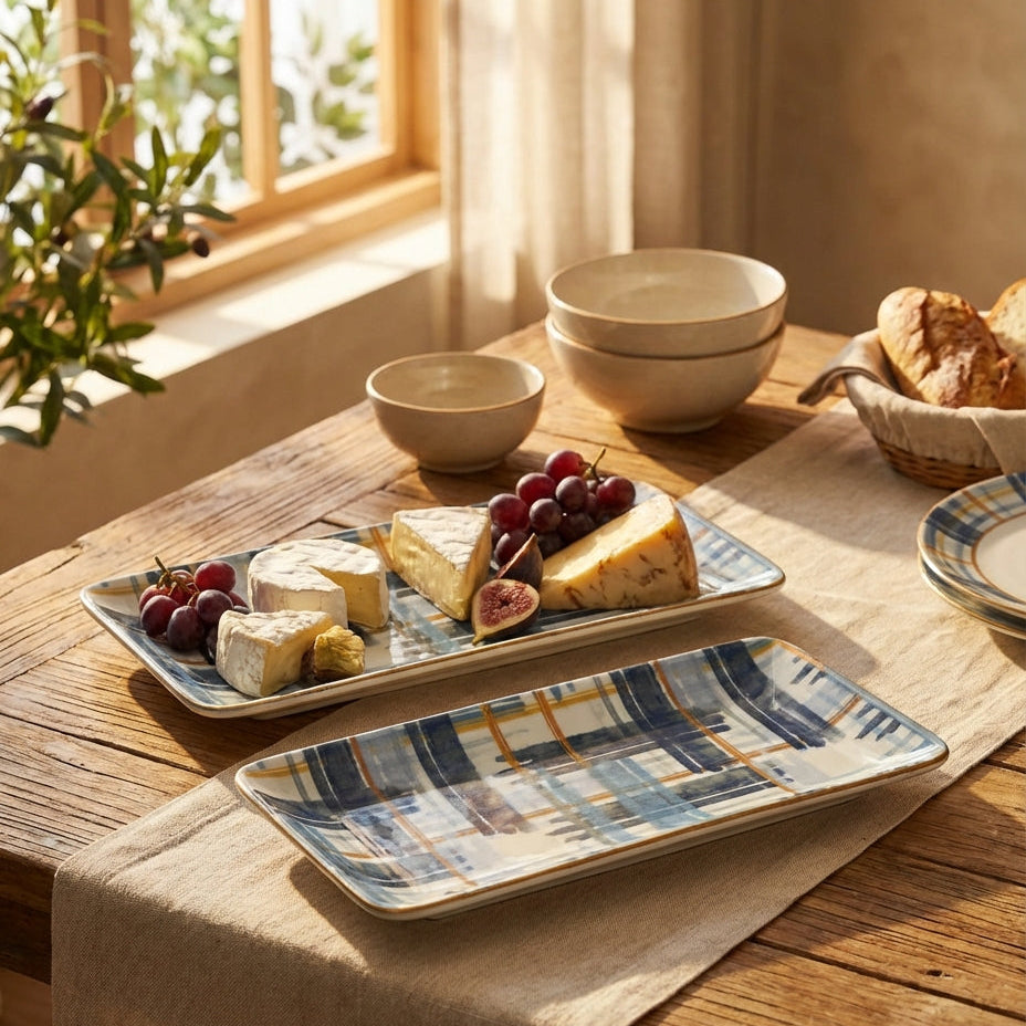 Dessert platter with cheese, fruits, and figs on a wooden table with bowls and bread in the background.
