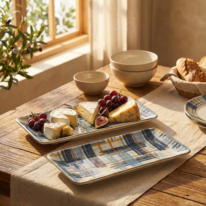 Dessert platter with cheese, fruits, and figs on a wooden table with bowls and bread in the background.