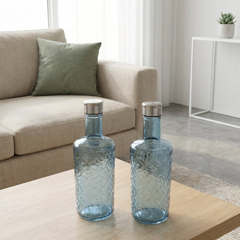 Two blue glass bottles on a wooden coffee table in a living room.