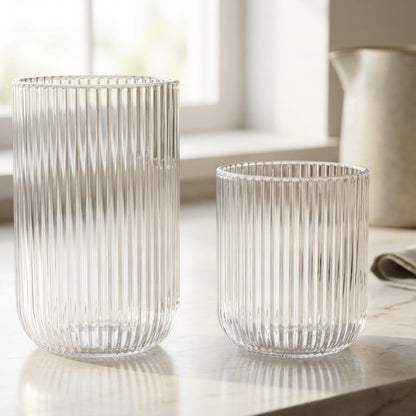 Two ribbed glass tumblers on a marble surface with a blurred background