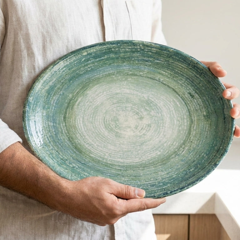 Person holding a green ceramic plate in a kitchen setting