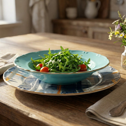 Teal bowl with salad on a wooden table with cutlery and flowers