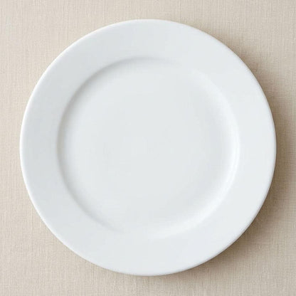 A plain white ceramic plate photographed from above on a light beige textured fabric background.