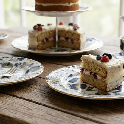 Cakes on a wooden table with floral plates and teacups.