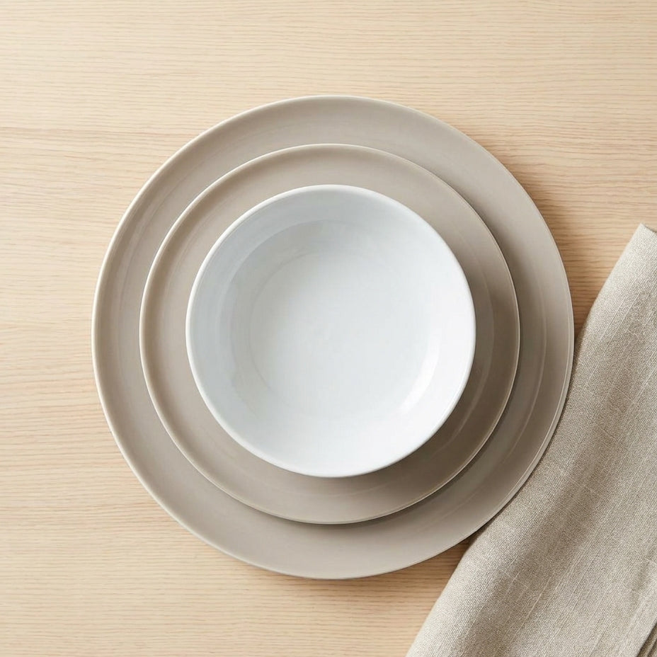 Stack of beige ceramic plates on a wooden surface with a beige napkin.