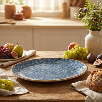 Blue ceramic plate on a wooden table with fruits and bread in a kitchen setting
