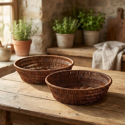 Two wicker baskets on a wooden table with potted plants in the background.