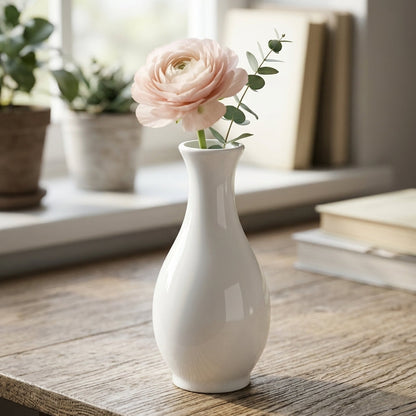 White vase with pink flower on a wooden table