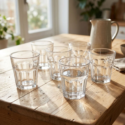 Set of six clear faceted drinking glasses on a wooden table