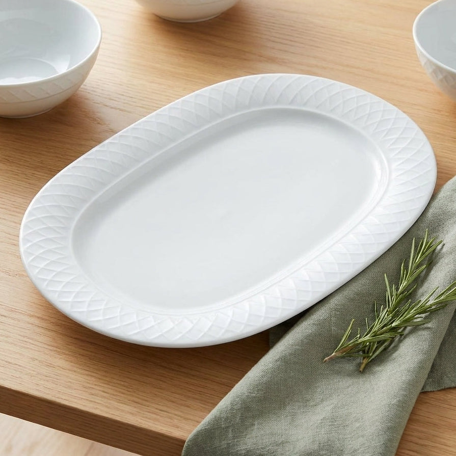 White ceramic platter on a wooden table with green napkin and rosemary.