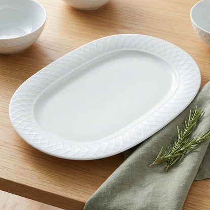 White ceramic platter on a wooden table with green napkin and rosemary.