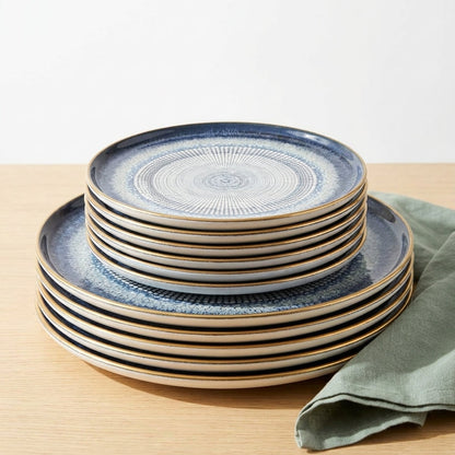 Set of blue ceramic plates stacked on a wooden surface with a green napkin.