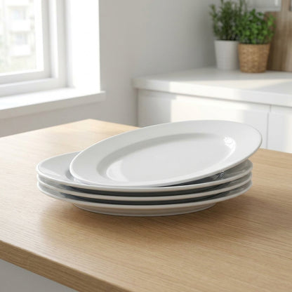 Stack of white oval plates on a wooden table with a kitchen background