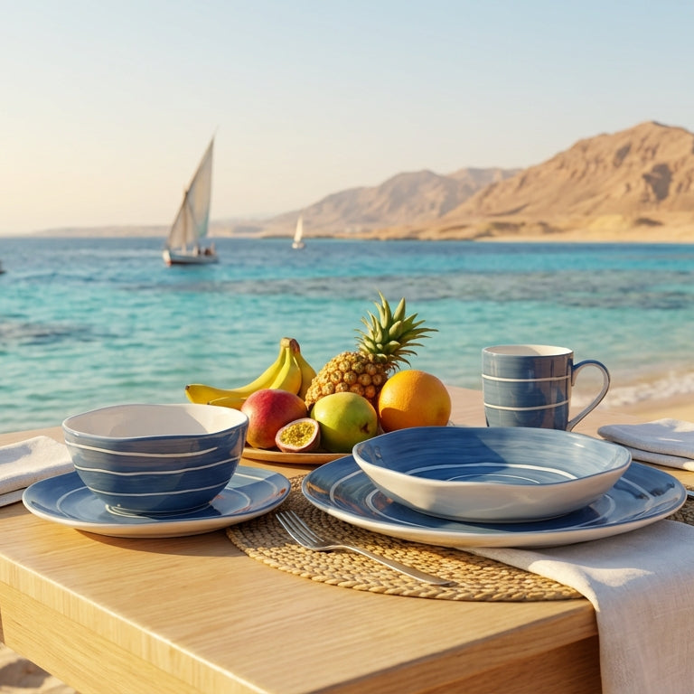 Dining setup on a beach with sailboats and mountains in the background