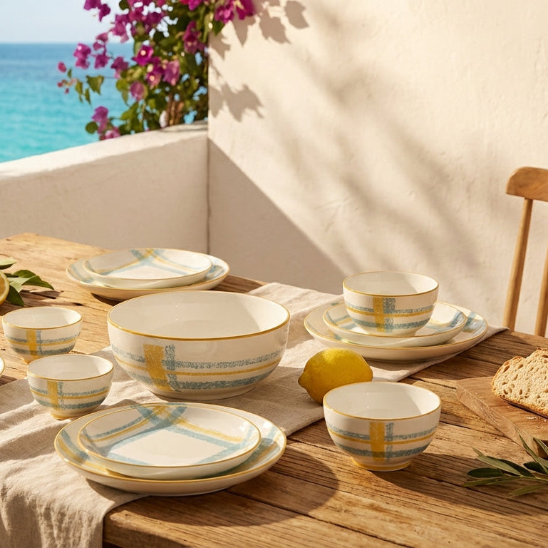 Dining table set with ceramic dishes and lemons by a window with a view of the ocean.