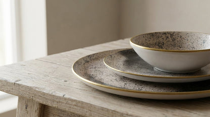 Speckled ceramic bowls and plates on a wooden table with a neutral background