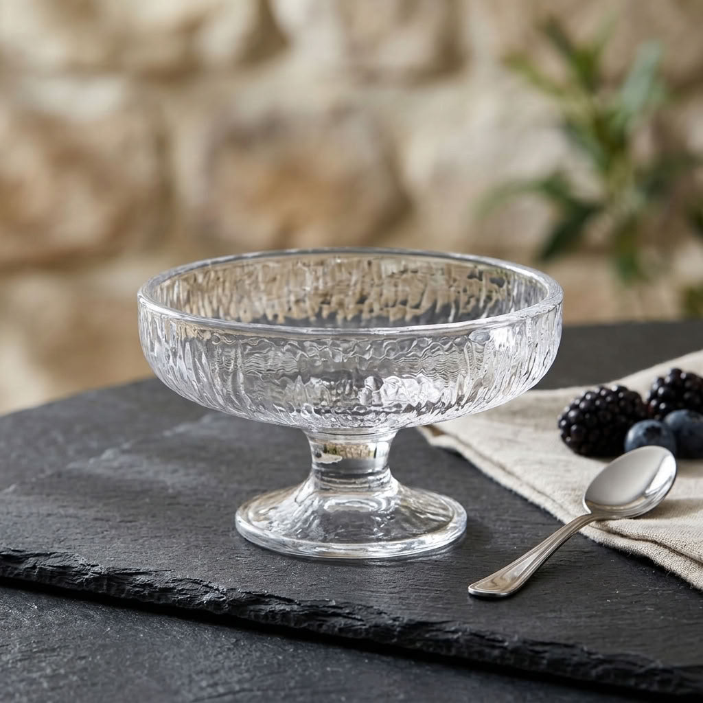 Clear textured glass dessert coupe with pedestal base on slate