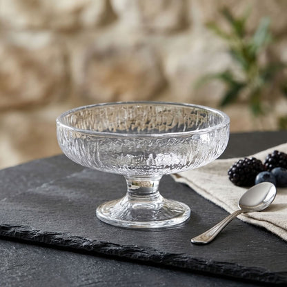 Clear textured glass dessert coupe with pedestal base on slate