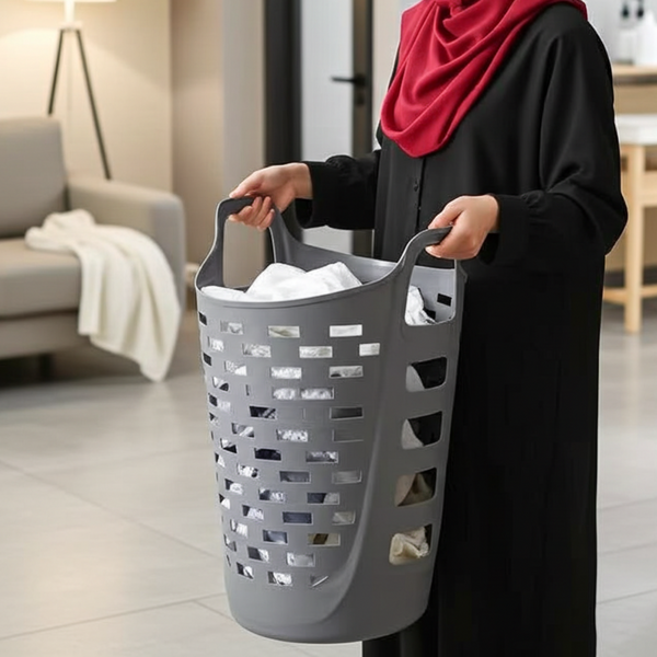 Woman holding a gray laundry basket filled with clothes in a modern living room.