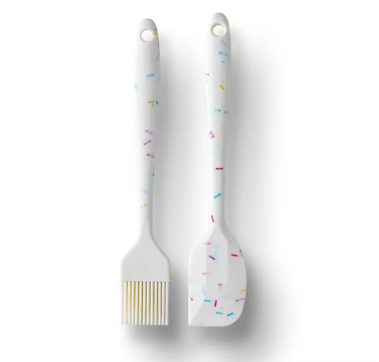 Two white silicone brushes with colorful sprinkles on a light gray background