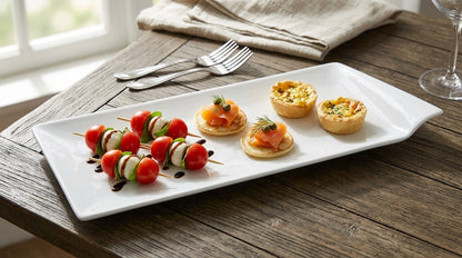 Plated appetizers including skewers and small pastries on a wooden table.