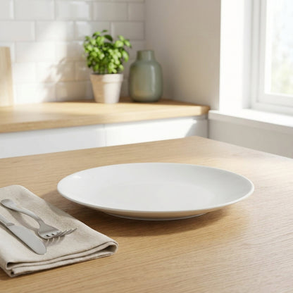 White plate on a wooden table with a napkin and cutlery in a kitchen setting