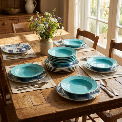 Dining table set with turquoise plates, silverware, and a vase of flowers in a sunlit room.