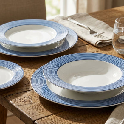 Set of white bowls with blue rims on a wooden table.