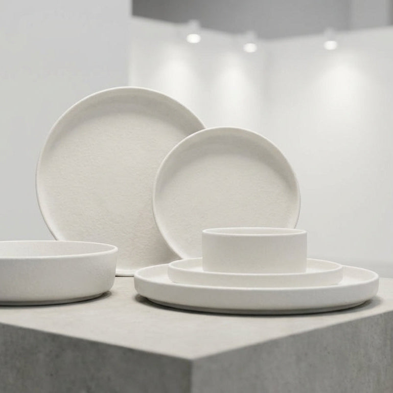 Set of white ceramic dishes on a gray platform with a neutral background