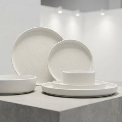 Set of white ceramic dishes on a gray platform with a neutral background