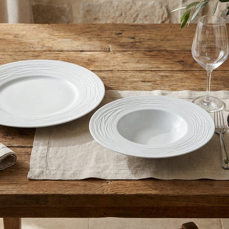 White ceramic plates on a wooden table with a stone wall background