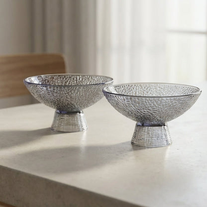 Two silver decorative bowls on a light-colored table with a blurred background