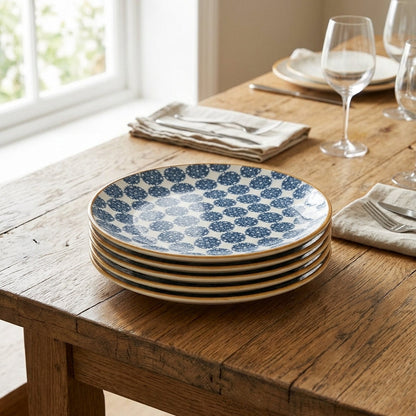 Stack of blue and white patterned plates on a wooden table with glasses and napkins.