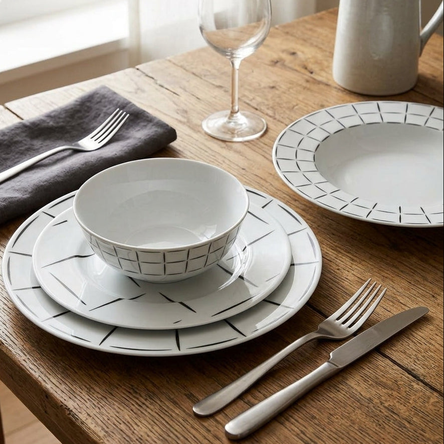 Dining table setting with ceramic plates, bowls, and cutlery on a wooden surface.