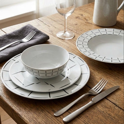Dining table setting with ceramic plates, bowls, and cutlery on a wooden surface.