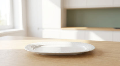 White plate on a wooden table with a blurred kitchen background