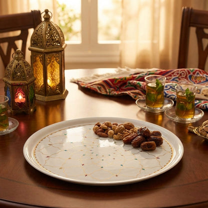 Dessert plate with dates and nuts on a wooden table with tea glasses and lanterns.