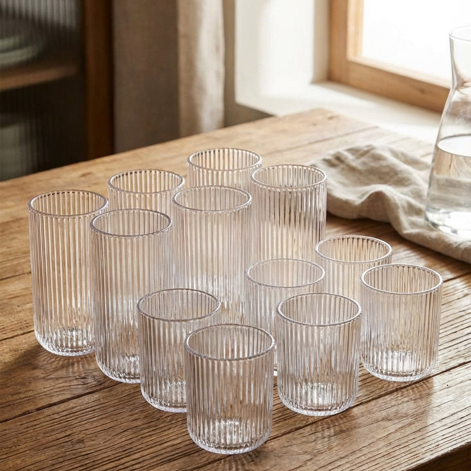 Set of clear glass tumblers on a wooden table with a window in the background.
