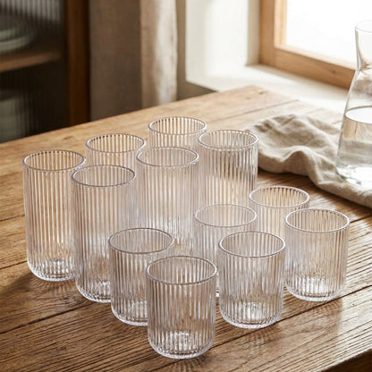 Set of clear glass tumblers on a wooden table with a window in the background.