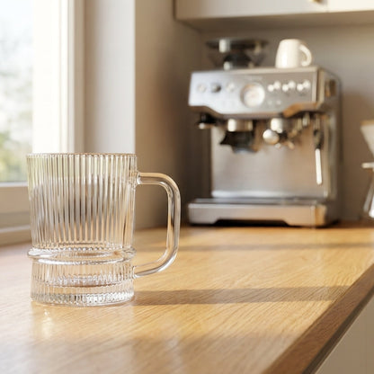 Clear glass mug on a kitchen counter with an espresso machine in the background